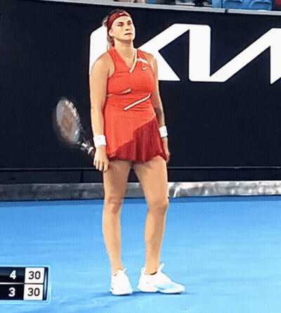 A Woman In A Red Dress Is Holding A Tennis Racket On A Blue Court GIF