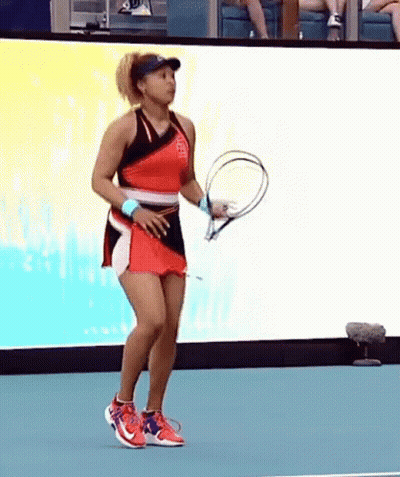A Woman In A Red Dress Is Holding A Tennis Racket On A Tennis Court . GIF