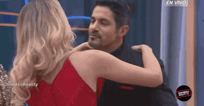 A Woman In A Red Dress Is Hugging A Man In A Black Shirt GIF