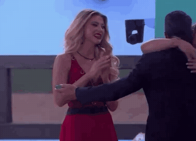 A Woman In A Red Dress Is Hugging A Man In A Black Suit GIF