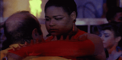 A Woman In A Red Dress Is Hugging A Man With A Bald Head GIF