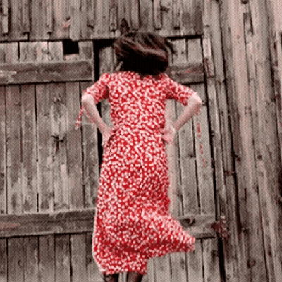 A Woman In A Red Dress Is Jumping In The Air GIF