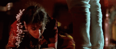 A Woman In A Red Dress Is Kneeling Down Next To A Man . GIF