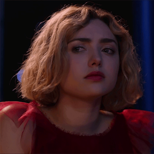 A Woman In A Red Dress Is Looking At The Camera GIF