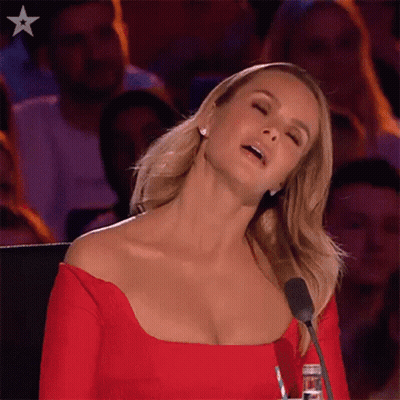 A Woman In A Red Dress Is Sitting At A Microphone With Her Eyes Closed . GIF