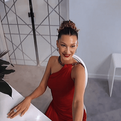 A Woman In A Red Dress Is Sitting At A White Table GIF
