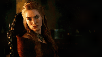 A Woman In A Red Dress Is Sitting In A Chair In A Dark Room And Looking At The Camera . GIF
