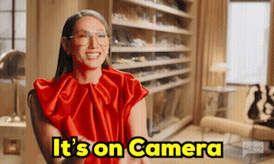 A Woman In A Red Dress Is Sitting In A Chair In Front Of A Closet . GIF