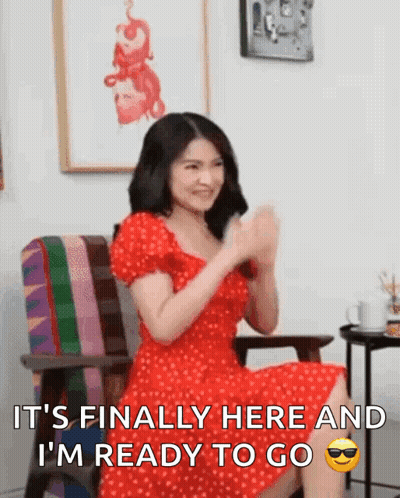 A Woman In A Red Dress Is Sitting In A Chair With Her Hands In The Air And Says It 'S Finally Here GIF