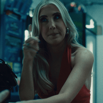 A Woman In A Red Dress Is Sitting In A Dark Room GIF