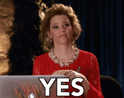 A Woman In A Red Dress Is Sitting In Front Of A Laptop And The Word Yes Is On The Screen GIF