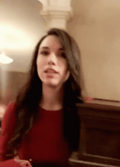 A Woman In A Red Dress Is Sitting In Front Of A Piano And Making A Funny Face . GIF