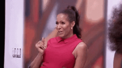 A Woman In A Red Dress Is Sitting In Front Of A Wall And Crying . GIF