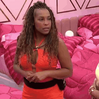 A Woman In A Red Dress Is Standing In A Bedroom With Pink Pillows . GIF