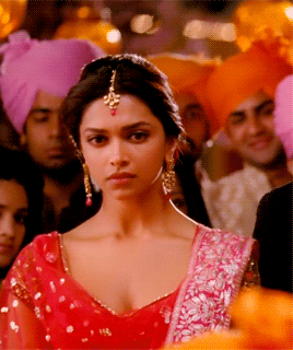 A Woman In A Red Dress Is Standing In A Crowd Of People GIF