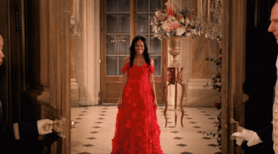 A Woman In A Red Dress Is Standing In A Doorway GIF