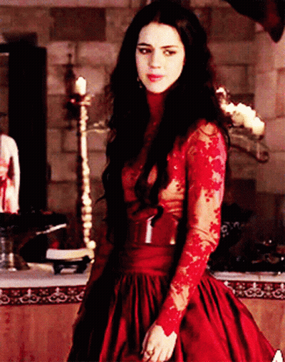 A Woman In A Red Dress Is Standing In A Room GIF