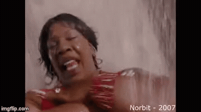 A Woman In A Red Dress Is Standing In A Shower And Laughing . GIF