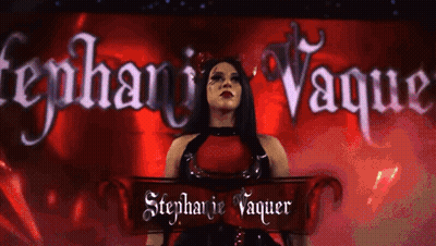 A Woman In A Red Dress Is Standing In Front Of A Banner That Says Stephanie Vaquer GIF