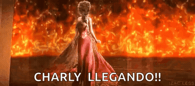 A Woman In A Red Dress Is Standing In Front Of A Fire With The Words Charly Llegando ! GIF