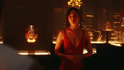 A Woman In A Red Dress Is Standing In Front Of A Glass Display GIF
