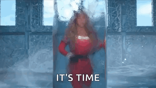 A Woman In A Red Dress Is Standing In Front Of A Glass Door And Says `` It 'S Time '' . GIF