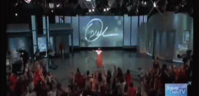 A Woman In A Red Dress Is Standing In Front Of A Large Screen That Says Ryan GIF