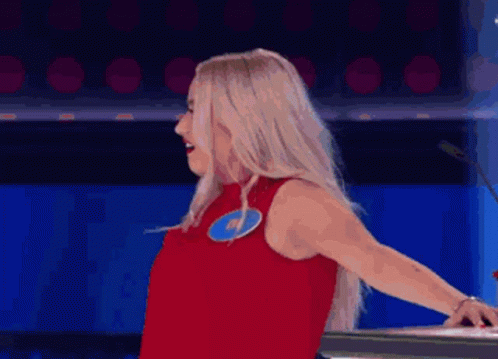 A Woman In A Red Dress Is Standing In Front Of A Microphone And Making A Funny Face . GIF