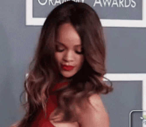 A Woman In A Red Dress Is Standing In Front Of A Wall . GIF