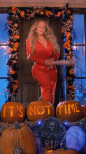 A Woman In A Red Dress Is Standing In Front Of Pumpkins That Say " It 'S Not Time " GIF