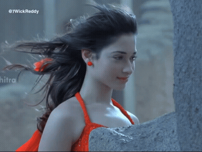 A Woman In A Red Dress Is Standing Next To A Wall With The Hashtag 7Wickreddy On The Bottom GIF