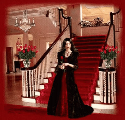 A Woman In A Red Dress Is Standing On A Set Of Stairs GIF