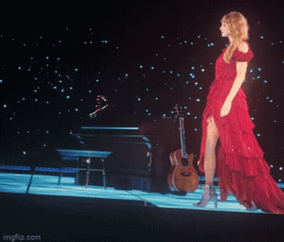 A Woman In A Red Dress Is Standing On A Stage With A Guitar GIF