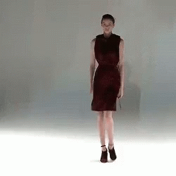 A Woman In A Red Dress Is Standing On A White Floor GIF