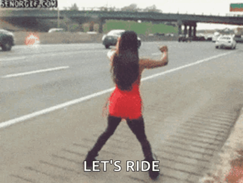 A Woman In A Red Dress Is Standing On The Side Of A Highway And Says Let 'S Ride .. GIF