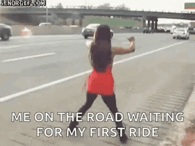 A Woman In A Red Dress Is Standing On The Side Of A Highway . GIF