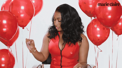 A Woman In A Red Dress Is Surrounded By Red Balloons With Marie Claire Written On The Balloons GIF