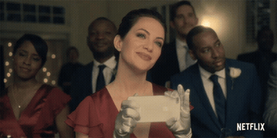 A Woman In A Red Dress Is Taking A Picture Of Herself With A Netflix Logo In The Background GIF