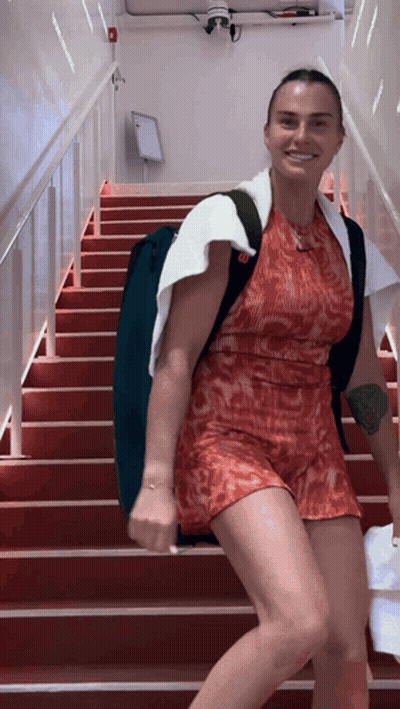 A Woman In A Red Dress Is Walking Down Stairs GIF