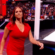 A Woman In A Red Dress Is Walking On A Stage . GIF