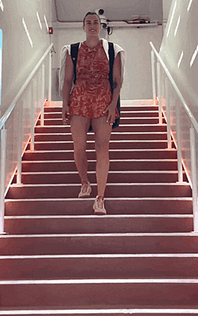 A Woman In A Red Dress Is Walking Up A Set Of Red Stairs GIF