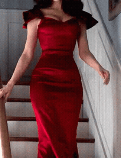 A Woman In A Red Dress Is Walking Up Stairs . GIF