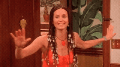 A Woman In A Red Dress Is Waving Her Hands In Front Of A Door . GIF
