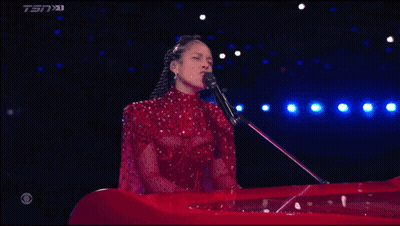A Woman In A Red Dress Singing Into A Microphone With Tsn On The Bottom Right GIF