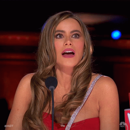 A Woman In A Red Dress Stands In Front Of A Microphone With Her Mouth Open And #Agt Written On The Bottom GIF