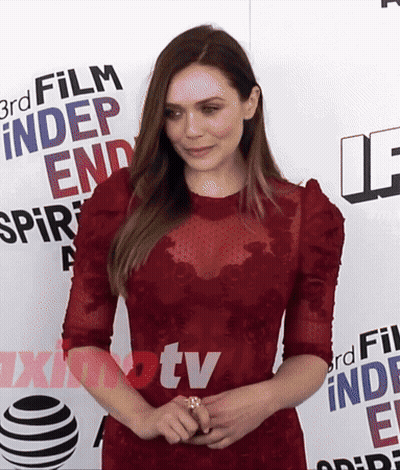 A Woman In A Red Dress Stands In Front Of A Sign That Says 3Rd Film Independent Spirit GIF