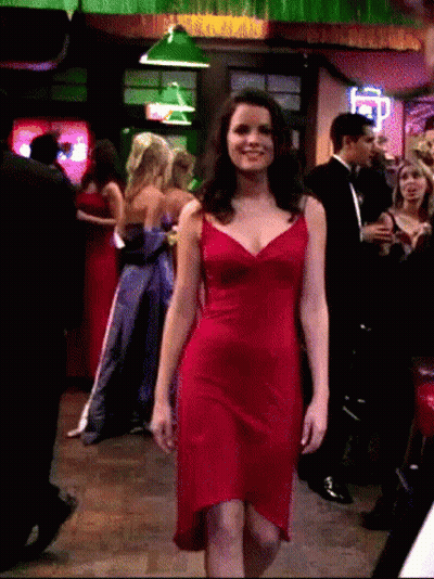 A Woman In A Red Dress Walks Through A Crowd GIF