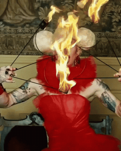 A Woman In A Red Dress With Flames Coming Out Of Her Head GIF