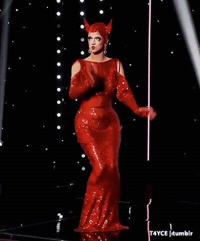A Woman In A Red Dress With Horns On Her Head Is Standing On A Stage . GIF