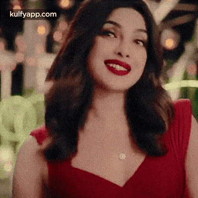 A Woman In A Red Dress With Red Lipstick Is Smiling . GIF